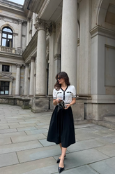 a lady in a white knit top and a black skirt